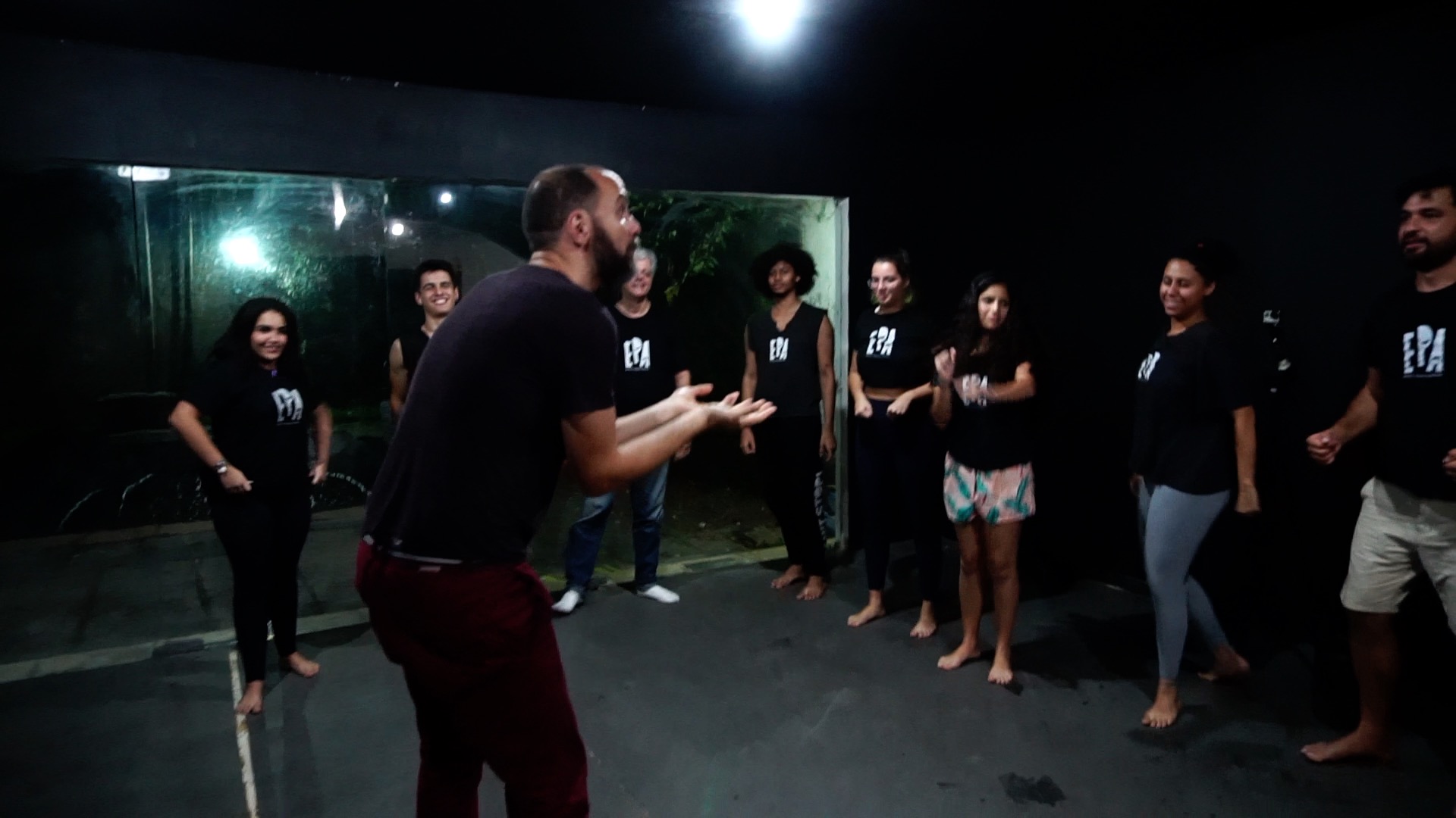 Pedro and a circle of performers practicing voice and movement